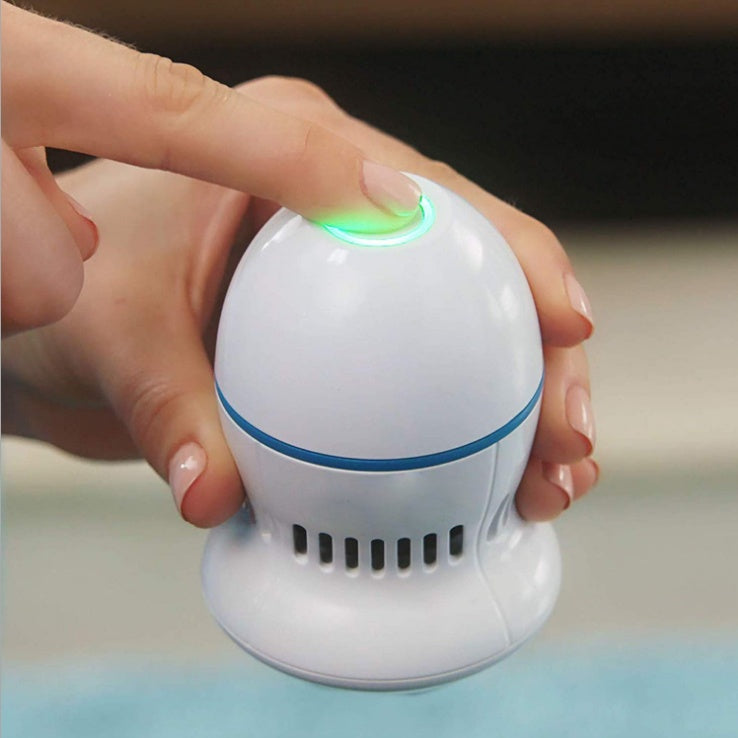 White electric foot file grinder device with glowing ring, held in hand