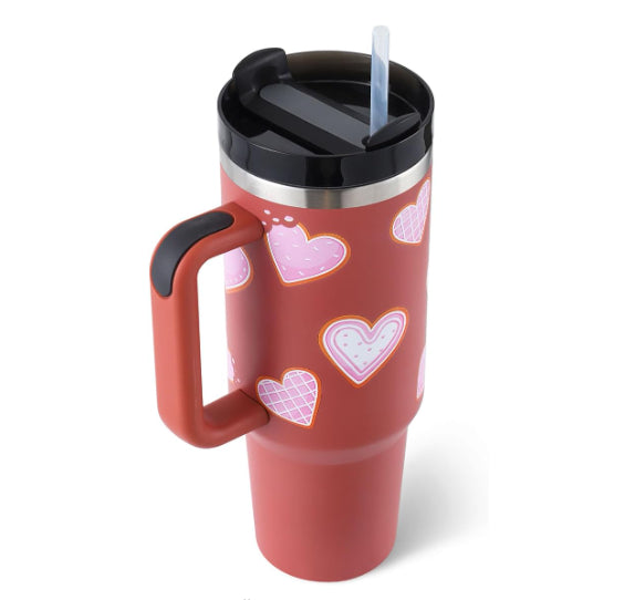 Insulated tumbler with handle, red heart pattern, straw and black lidded top.