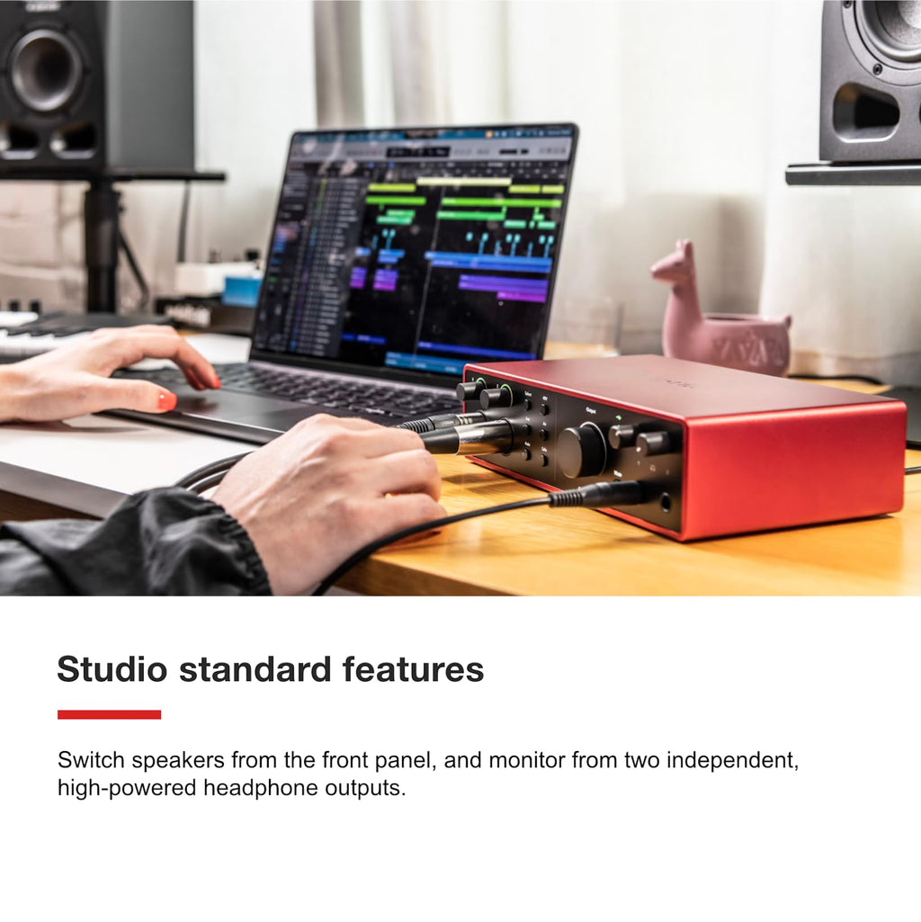 Focusrite Scarlett 18i16 USB audio interface on wooden desk with cables connected and hand near controls