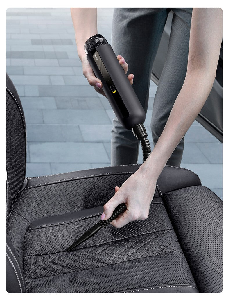 Handheld mini vacuum cleaner cleaning car seat upholstery with nozzle attachment.