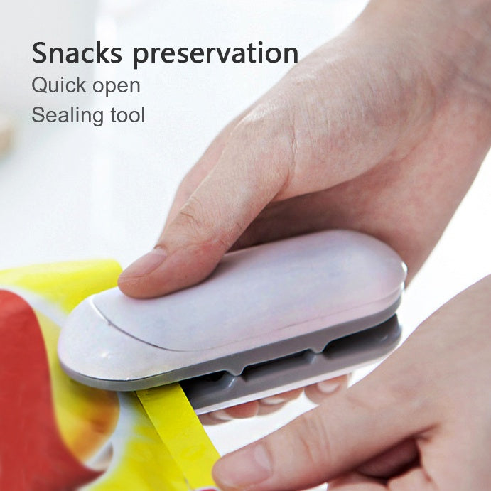 Mini portable heat sealer tool with white body held by hands over a plastic snack bag