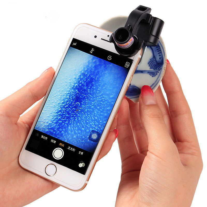 Black clip-on magnifying lens with built-in light attached to a smartphone