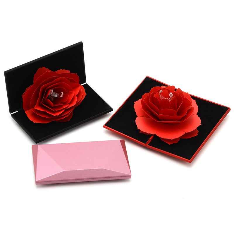 Heart-shaped rose ring boxes with red flowers on black inserts, plus pink base